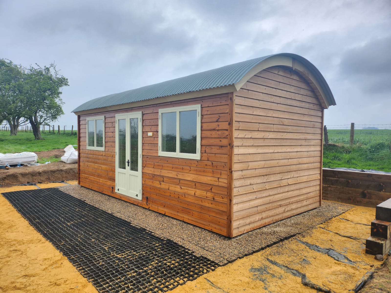 Extra-large wooden shepherd hut with arched roof and double doors.