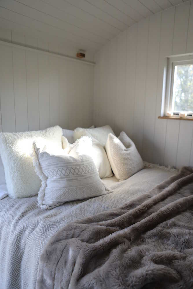 A bed set up inside of a shepherd hut.