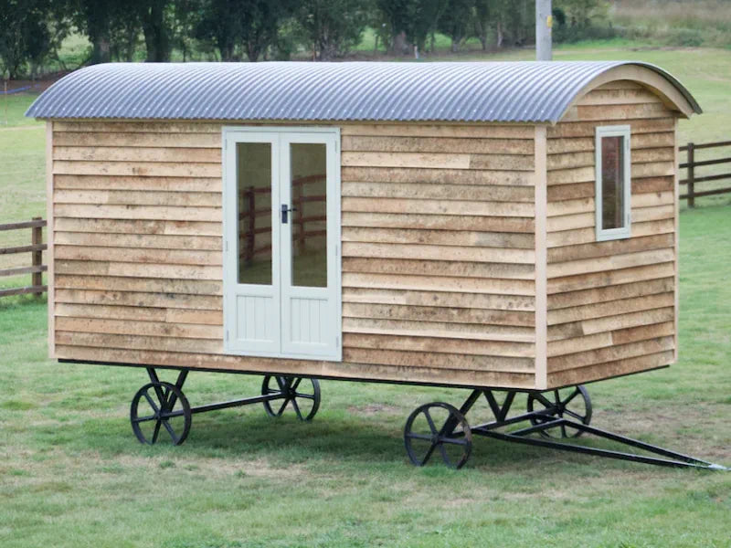 Wooden shepherd hut with french doors on a chassis.