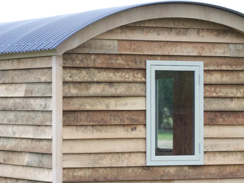 A pre-built shepherd's hut with a small window and corrugated roof from Harrogate Huts.