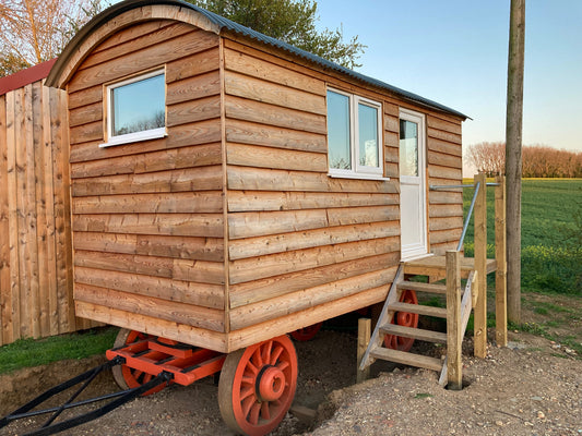Wooden shepherd hut with small double casement window.
